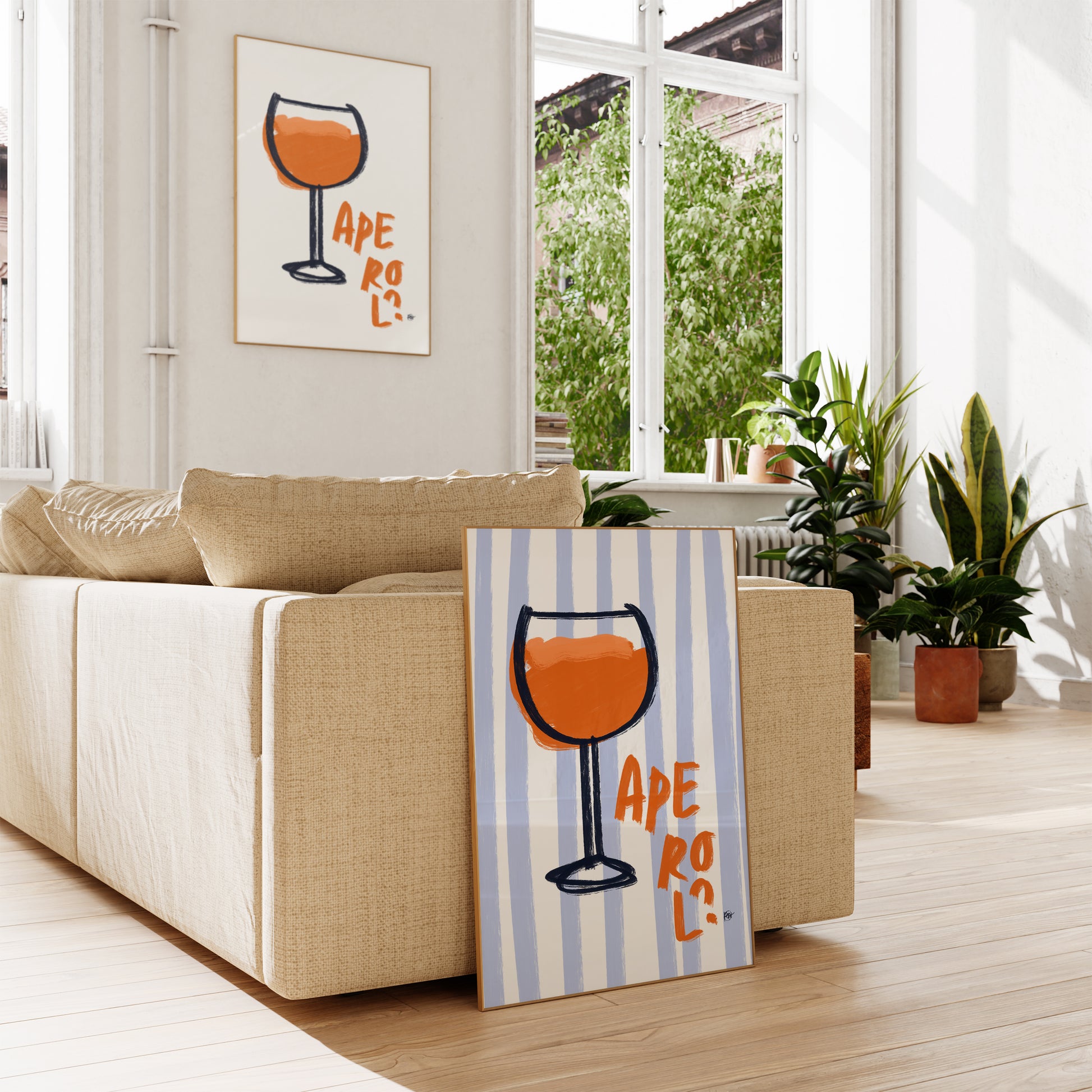 Living room with a beige sofa, striped towel with a glass design, and a window view with two frames aperol spritz prints.