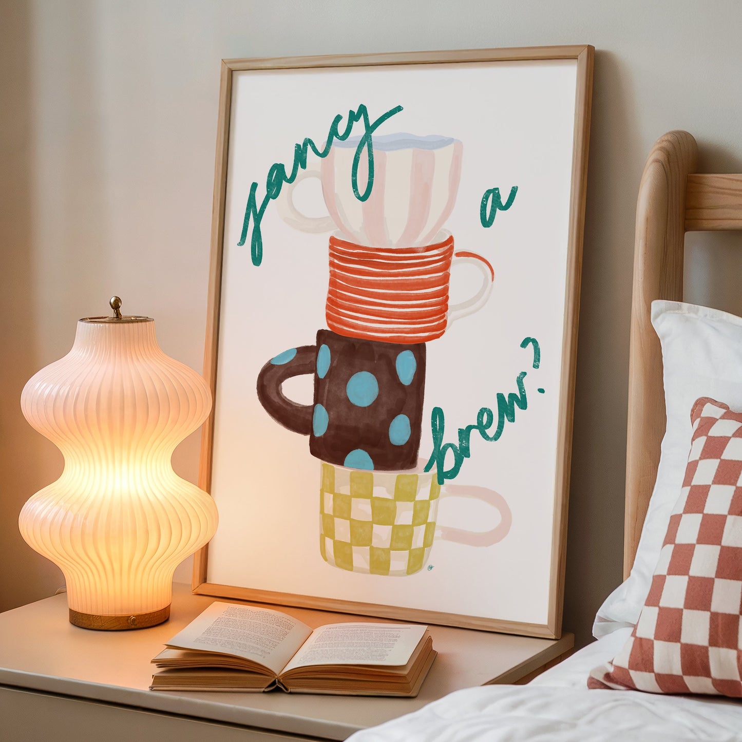 framed artwork of four colourful mugs and fancy a brew text on a beside table with a lamp