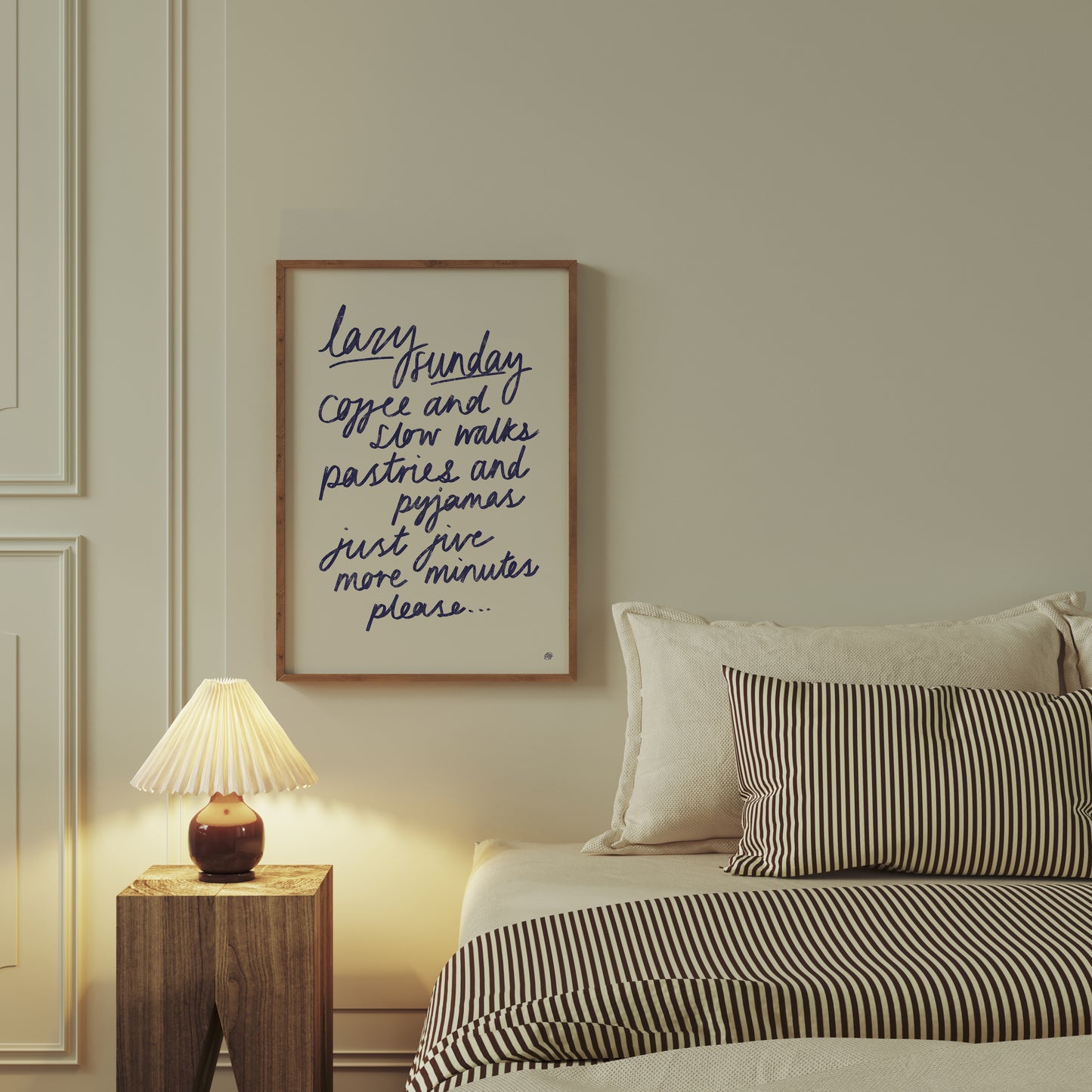 Bedroom with striped bedding, nightstand, and framed artwork on the wall.