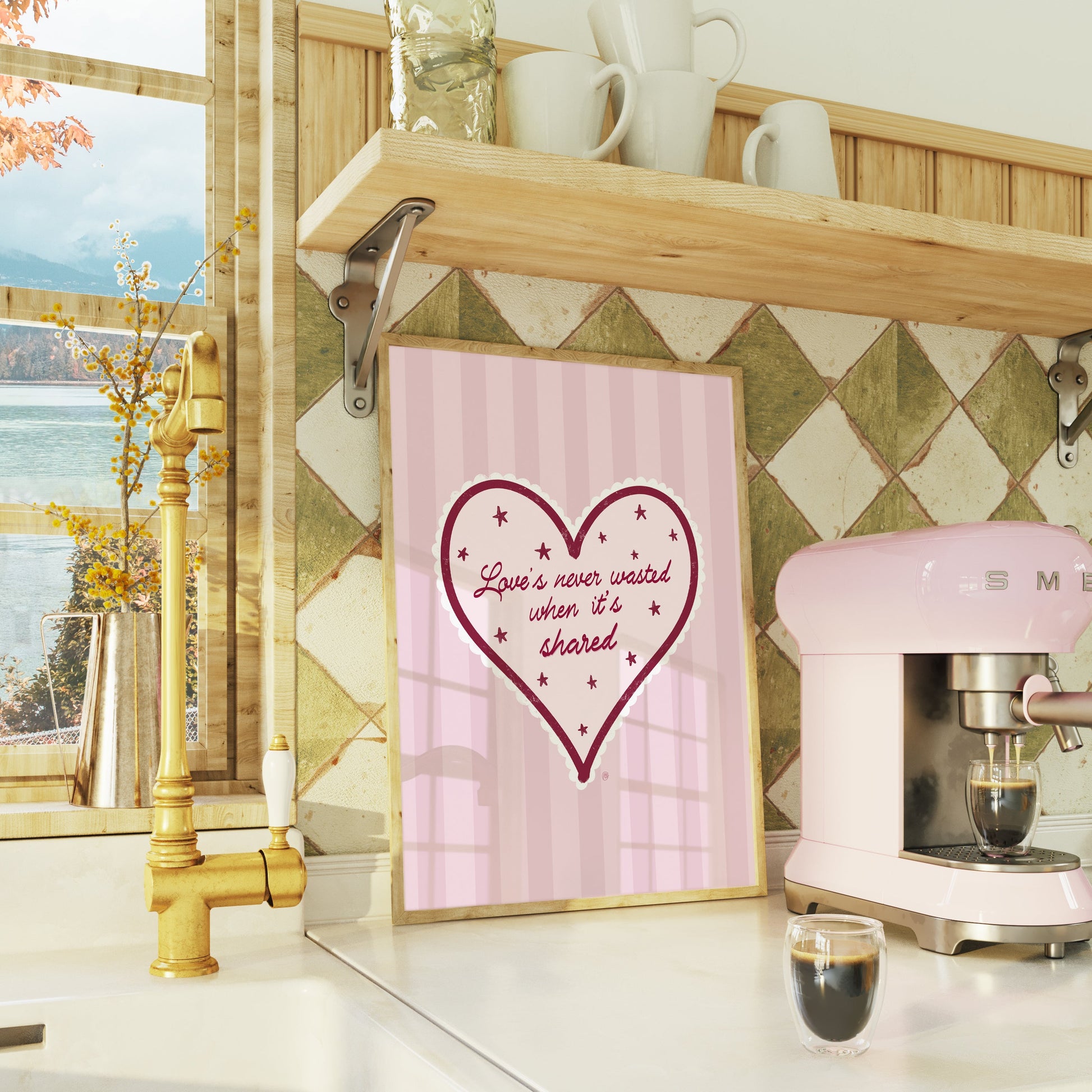 green and wooden kitchen setting with a bright window and a pink coffee machine and pink framed artwork on the wall of love is never wasted when its shared lyrics