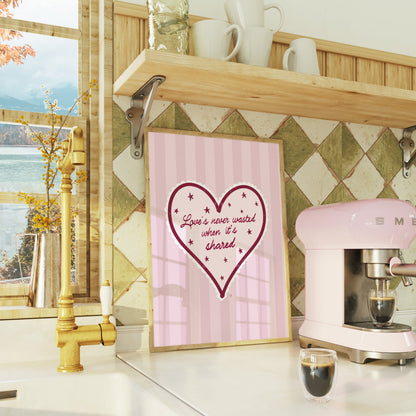 green and wooden kitchen setting with a bright window and a pink coffee machine and pink framed artwork on the wall of love is never wasted when its shared lyrics