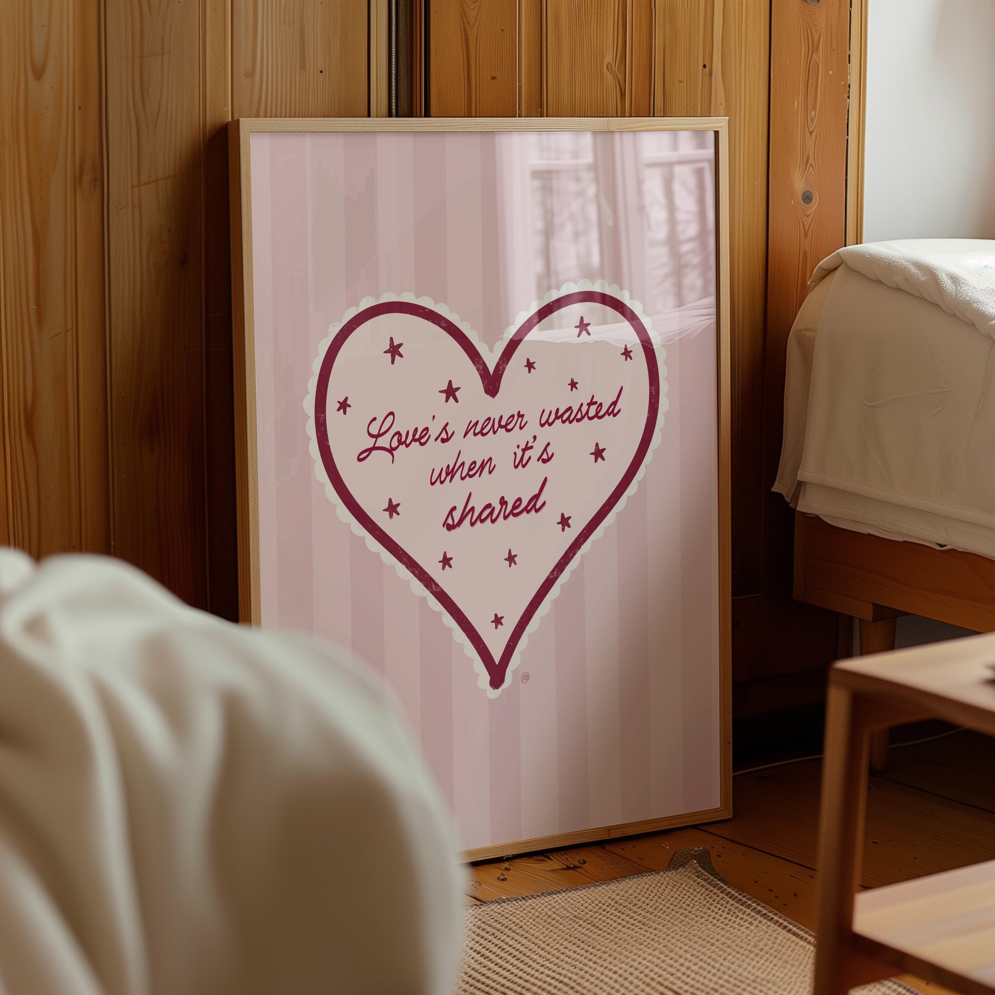 Framed artwork with a heart design and text on a wall in a room.