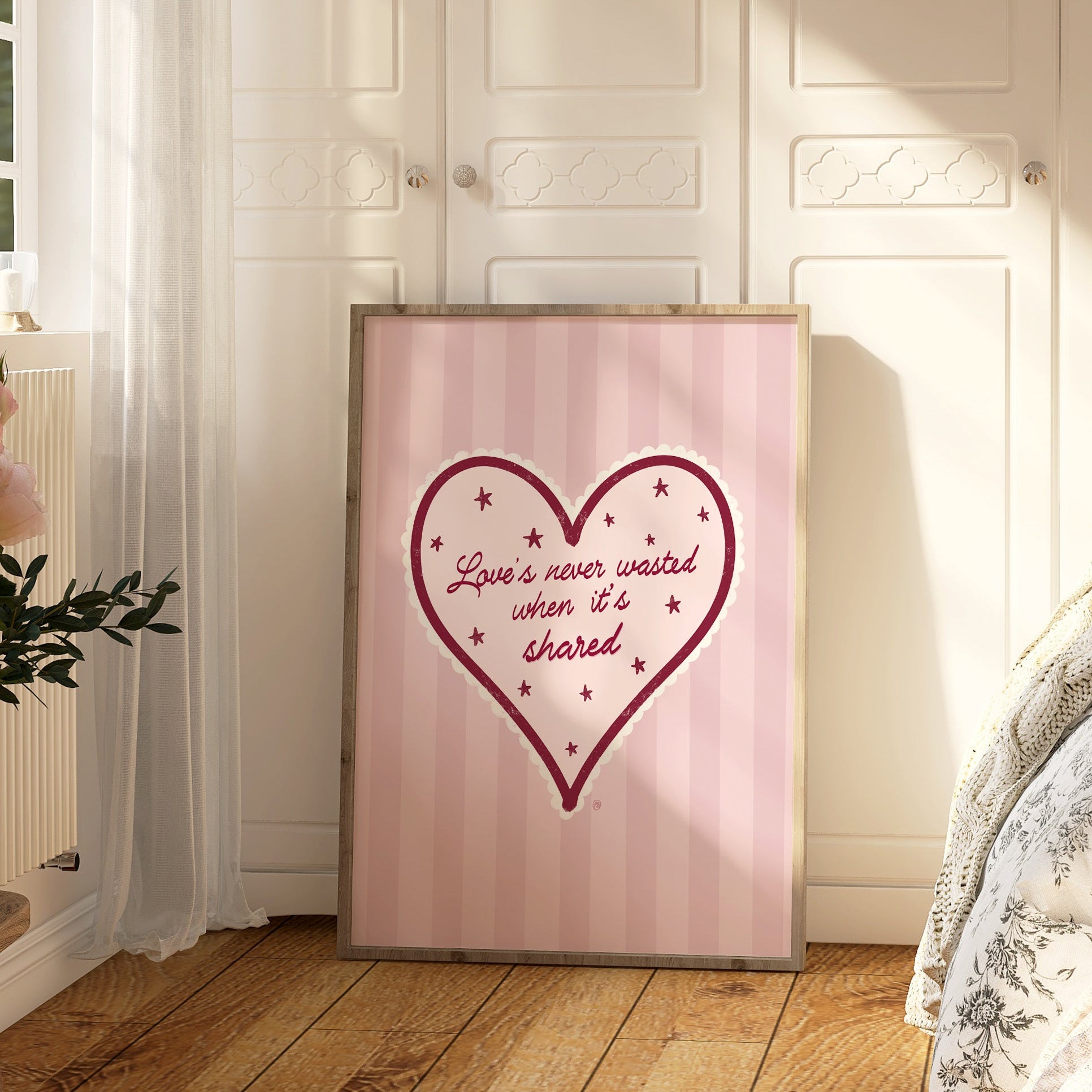 Framed heart-shaped artwork with text on a wall in a bedroom.
