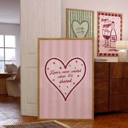 Framed heart-shaped artwork with text on a wall in a room.