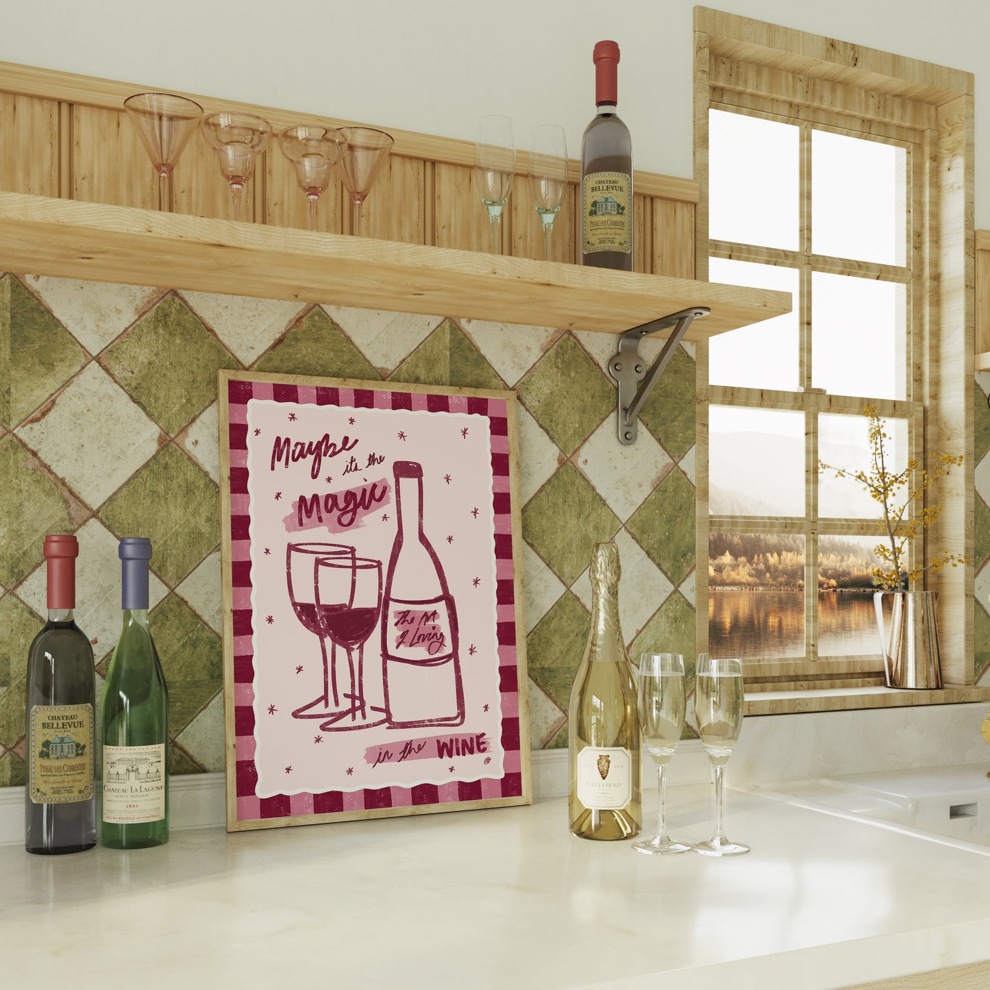 framed artwork of a bottle of wine and two wine glasses with a pink checked border on top of a kitchen counter with green tiles and champagne