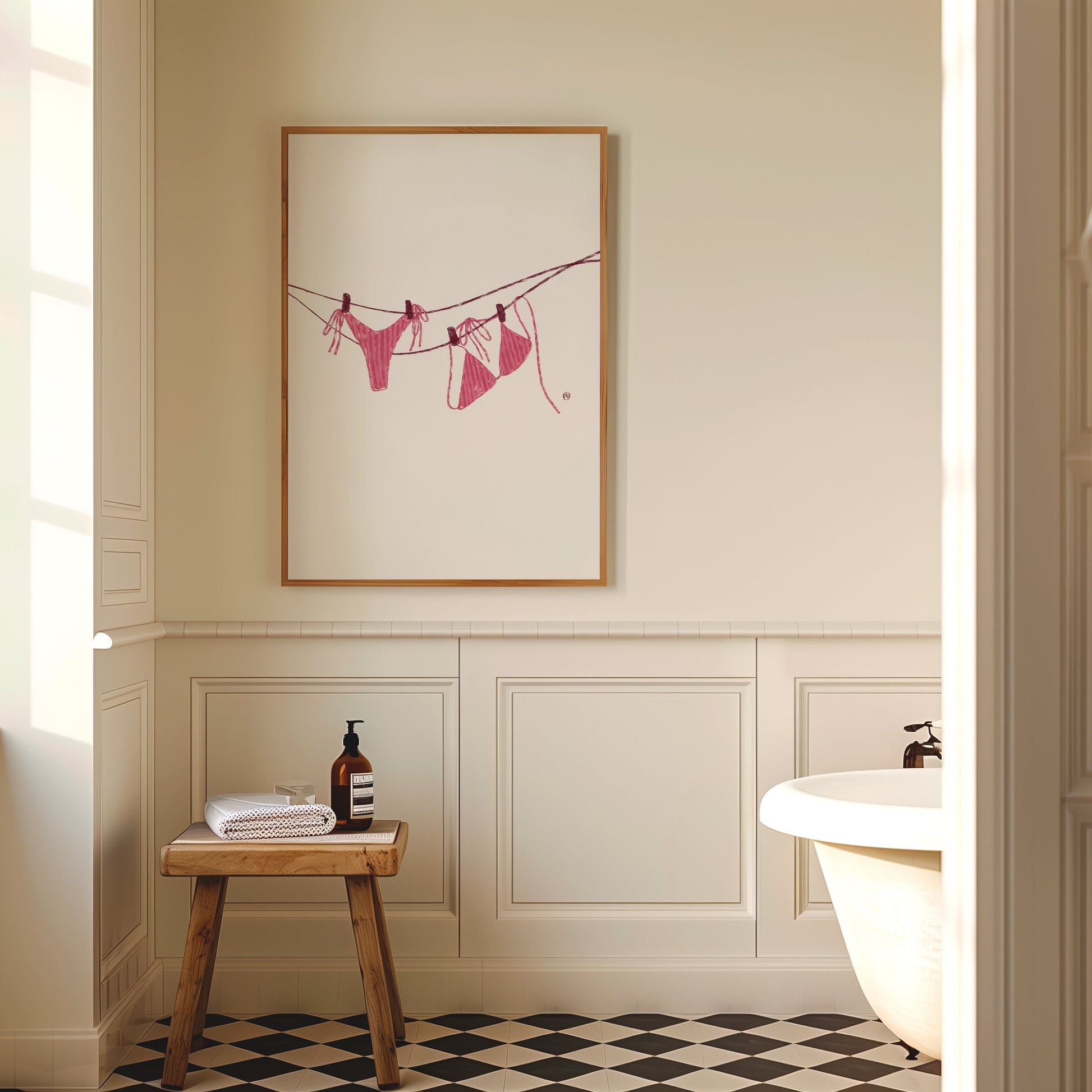 Bathroom interior with a framed PINK BIKINI artwork on the wall, wooden stool, and bathtub.