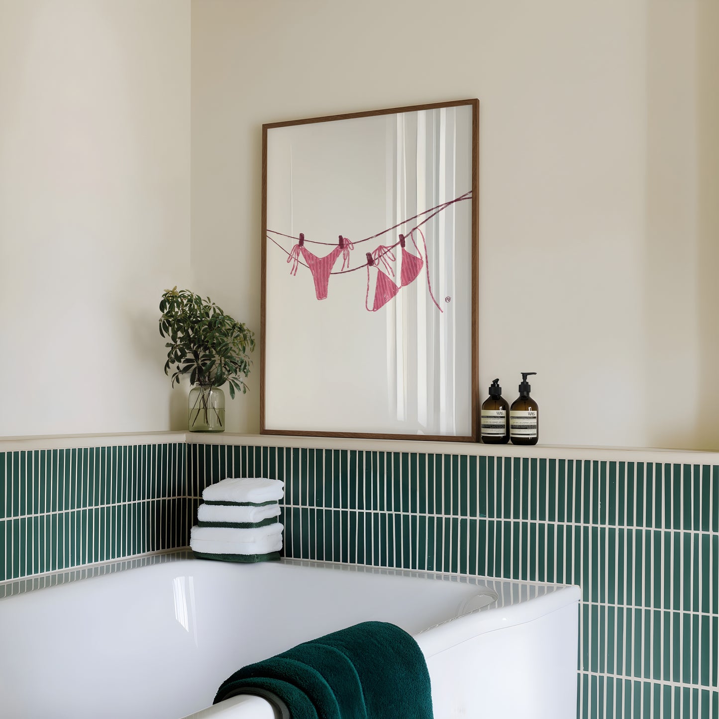 Bathroom with a framed artwork of a pink bikini on the wall, green tiles, and towels.