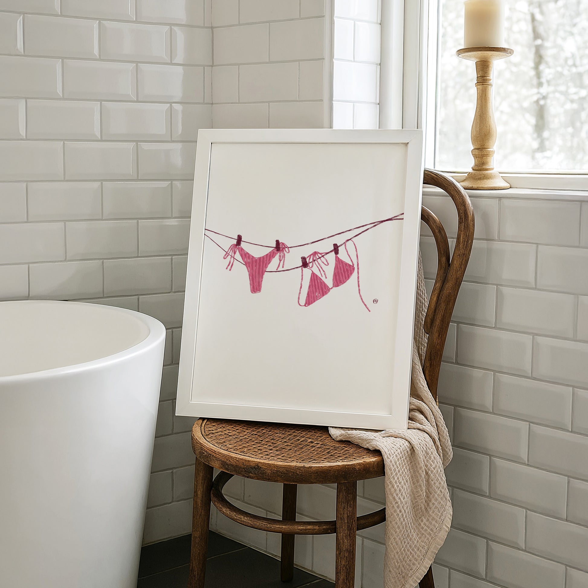 Framed artwork of a pink bikini on a clothesline in a bathroom setting.