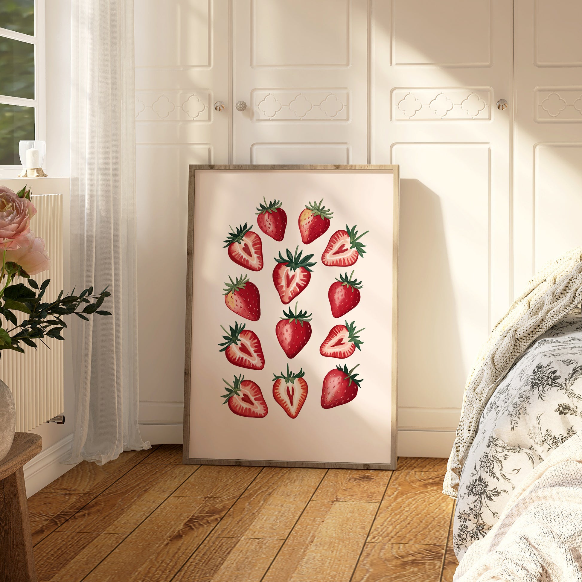 Framed artwork of strawberries on a wall in a room with wooden floor and white curtains.