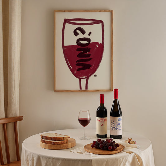 Wine-themed decor with bottles, glasses, and grapes on a table, framed artwork in the background.
