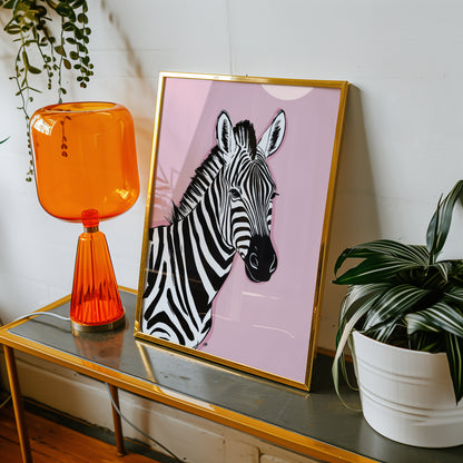 Framed pink zebra print on a table with an orange lamp and plant