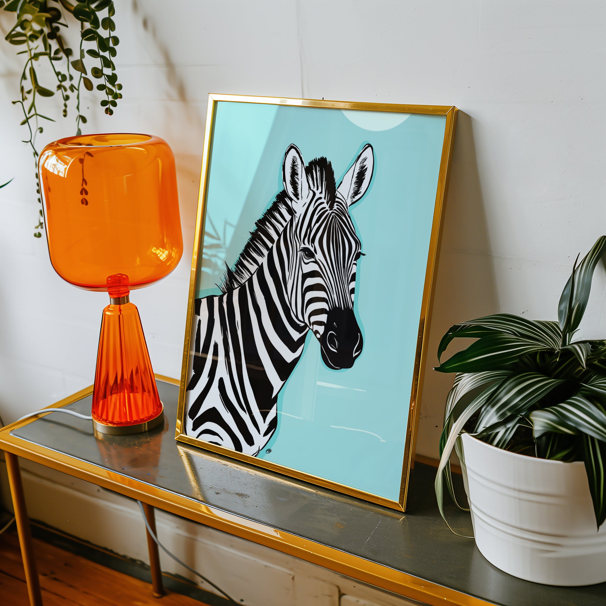 Framed zebra artwork on a table with an orange lamp and plant